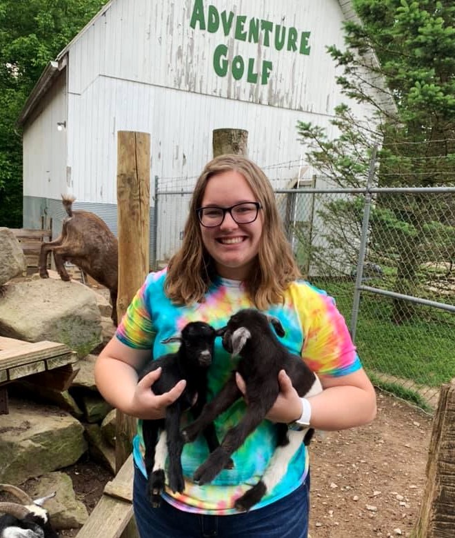 Girl holding two baby goats